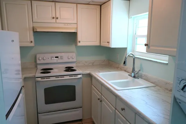 a kitchen with granite countertop a sink a stove and cabinets