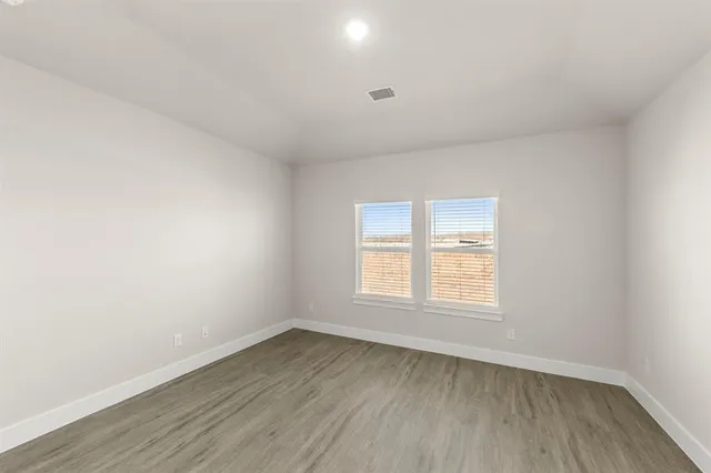 an empty room with wooden floor and window