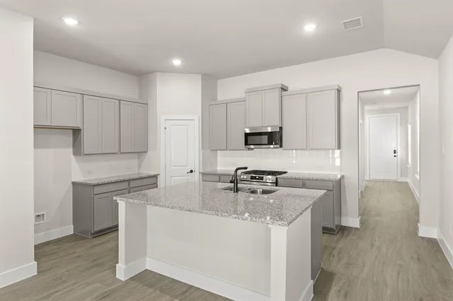 a kitchen with stainless steel appliances granite countertop a sink stove and refrigerator