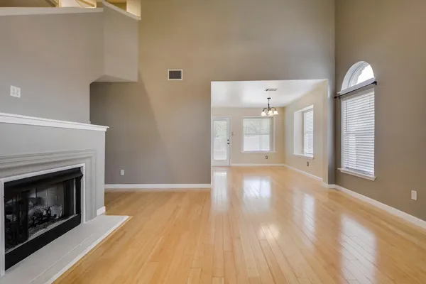 a view of an empty room with wooden floor and a fireplace