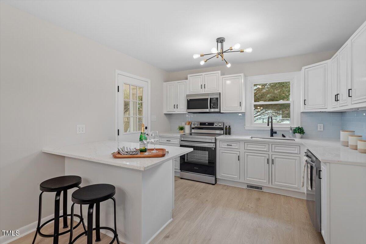 3408 Brentwood Road Raleigh, NC 27604 - Photo 5 of 41 a kitchen with stainless steel appliances a stove a sink cabinets and a microwave