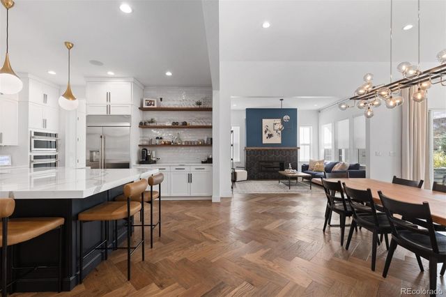 a kitchen with stainless steel appliances kitchen island granite countertop a table chairs and a refrigerator