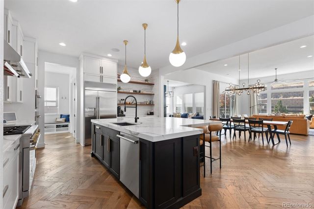 a open kitchen with stainless steel appliances granite countertop a stove a refrigerator a kitchen island a dining table and chairs