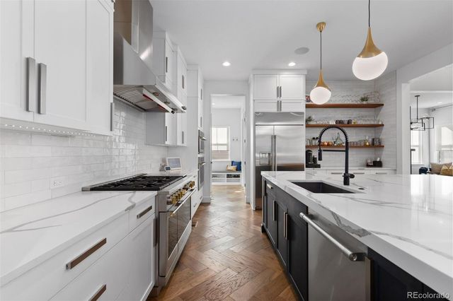 a kitchen with stainless steel appliances granite countertop a sink a stove and a wooden floors
