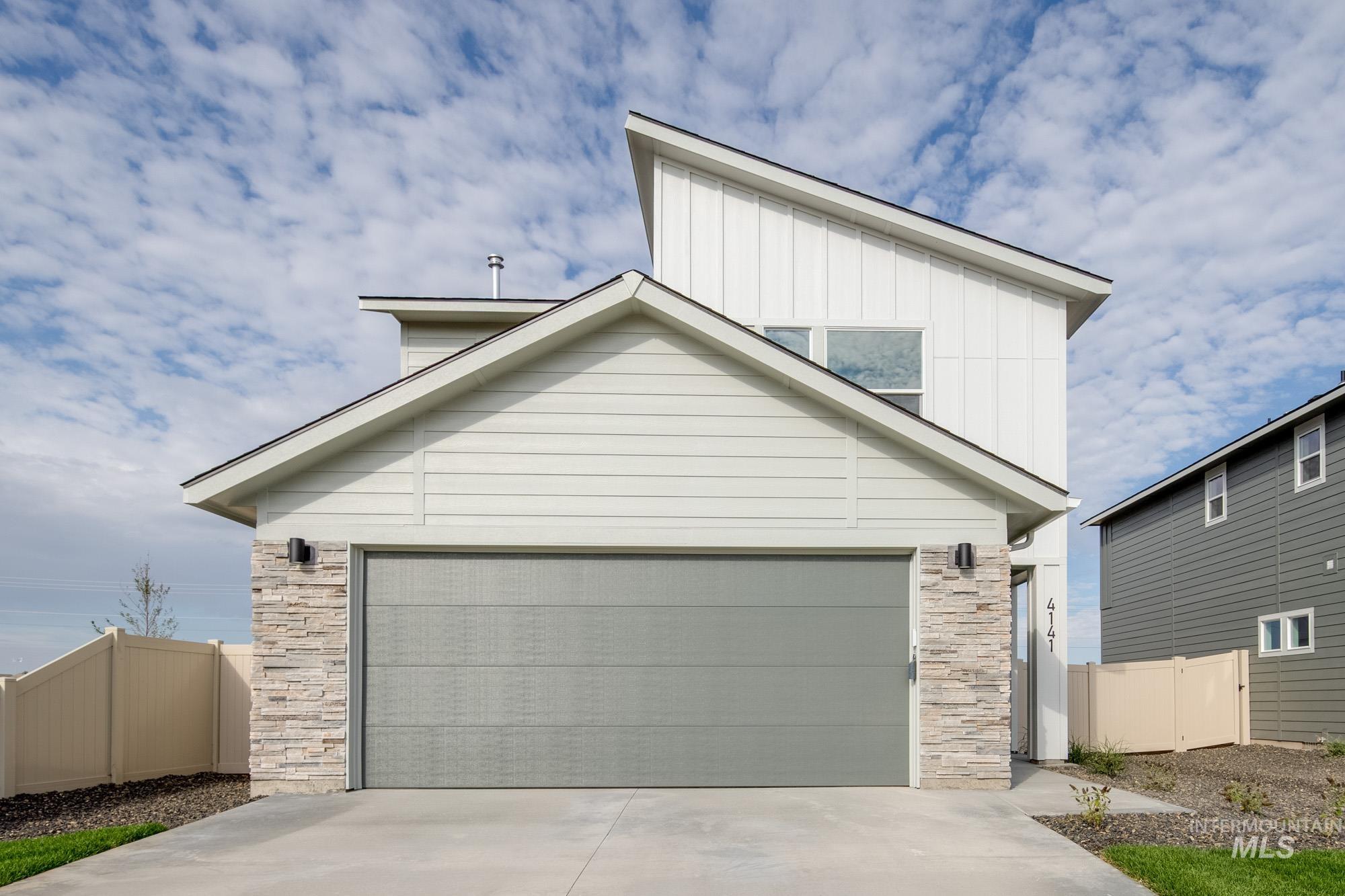 View of front of home featuring stone siding, driveway, board and batten siding, and an attached garage