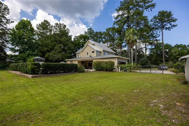 an aerial view of residential house with outdoor space and trees all around