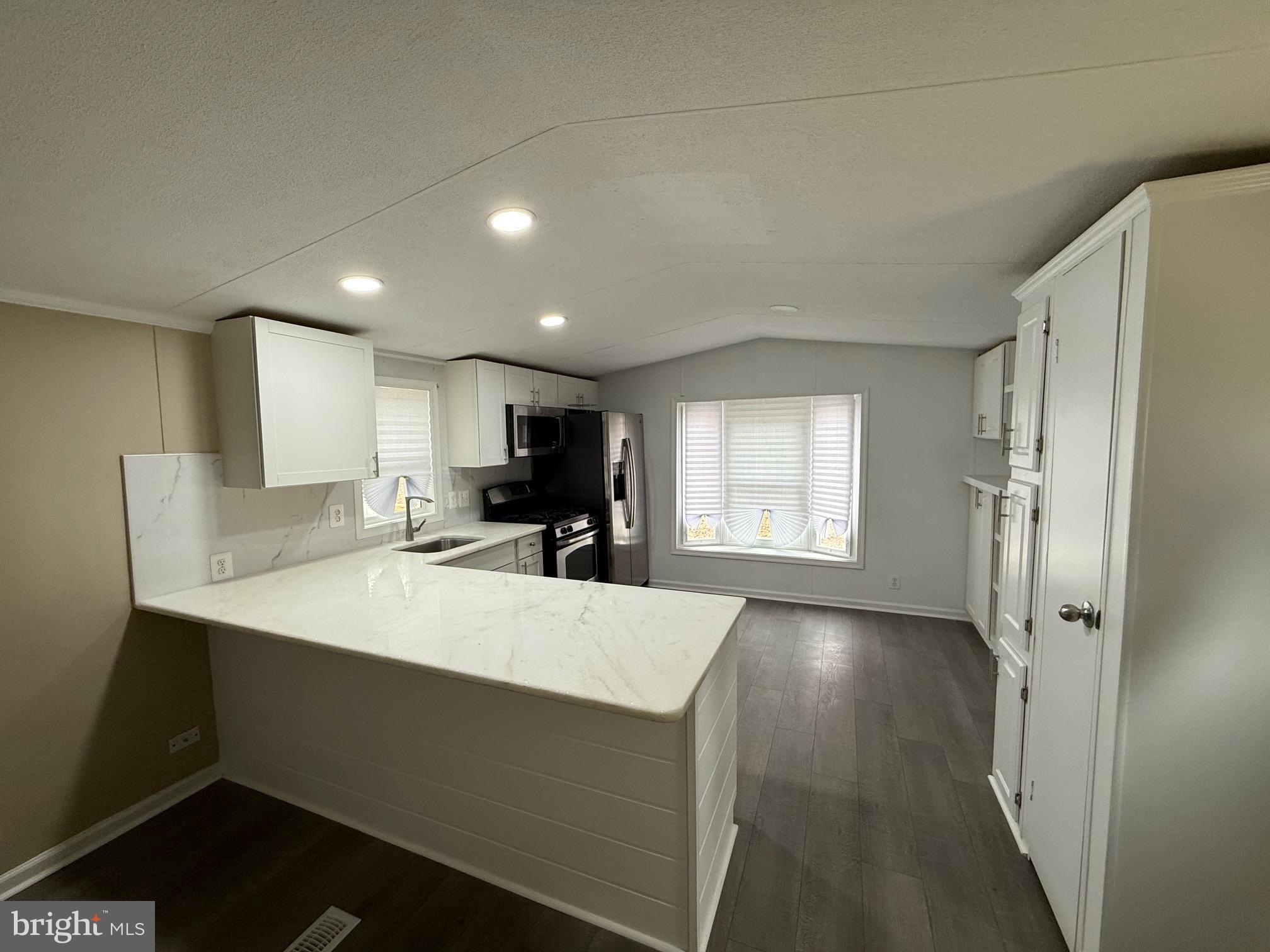 21182 Marsh Creek Road Preston, MD 21655 - Photo 2 of 9 a large white kitchen with wooden floor and a refrigerator