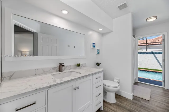 a bathroom with a granite countertop sink mirror and toilet