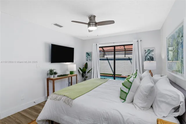 a bedroom with a bed window tv and table