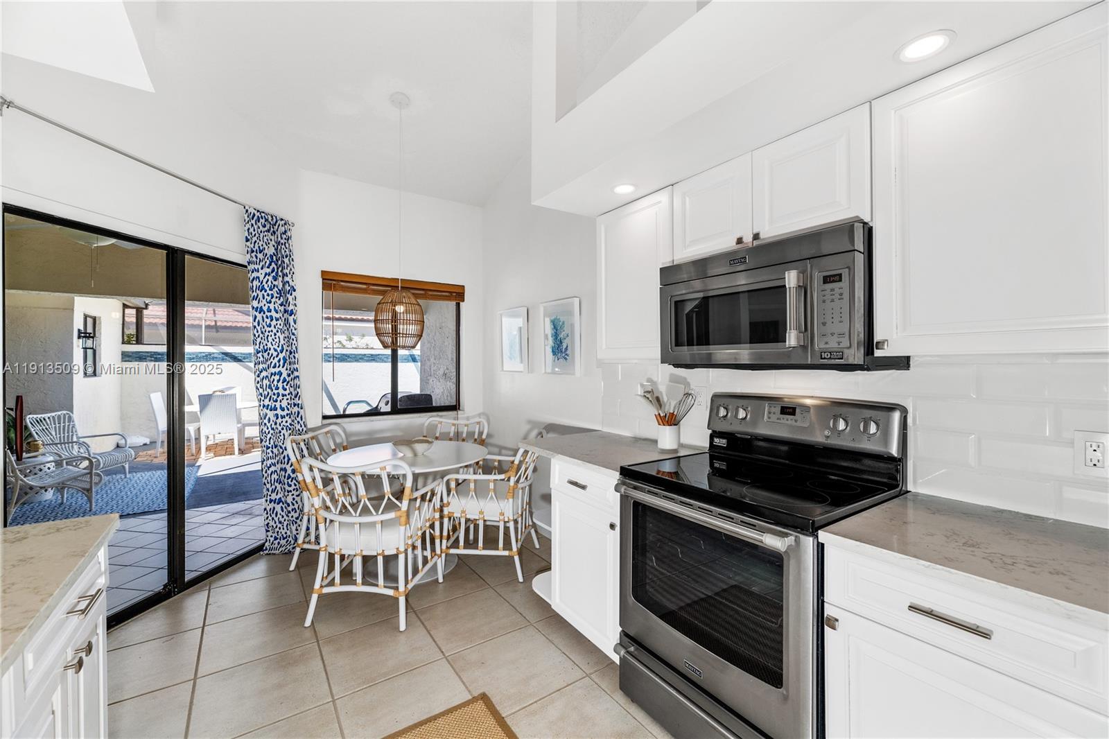 701 Sea Oats Drive, Unit D1 Juno Beach, FL 33408 - Photo 9 of 27 a kitchen with stainless steel appliances a stove a sink a microwave a dining table and chairs