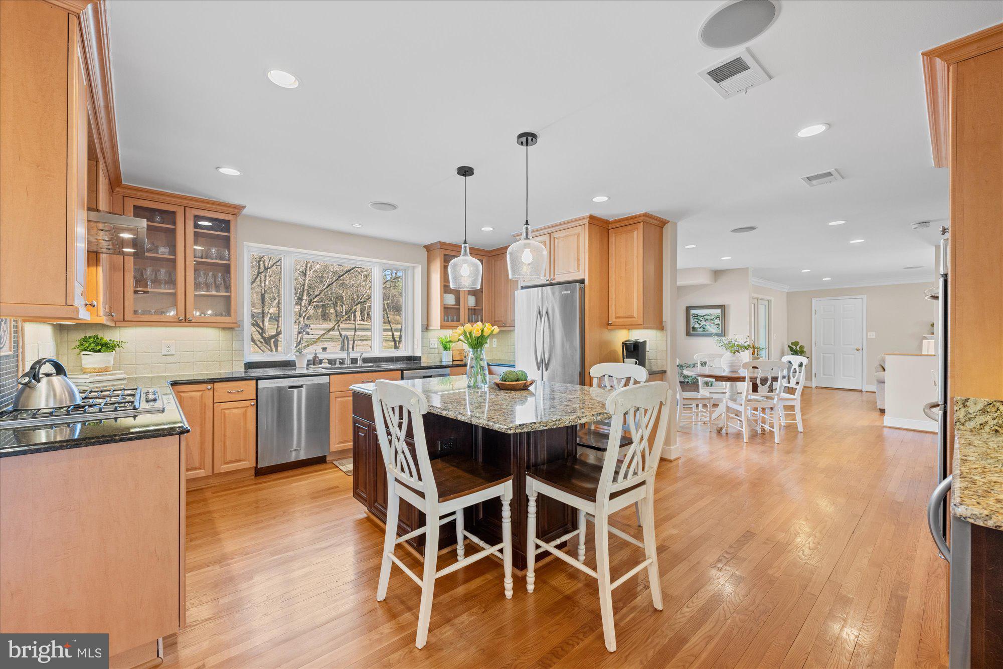 13321 Glen Mill Road Rockville, MD 20850 - Photo 6 of 31 a dining area with stainless steel appliances kitchen island granite countertop wooden floor a dining table and chairs