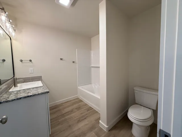 a bathroom with a granite countertop toilet a sink and a mirror
