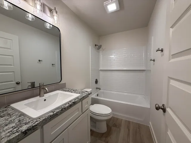 a bathroom with a granite countertop sink a toilet and shower