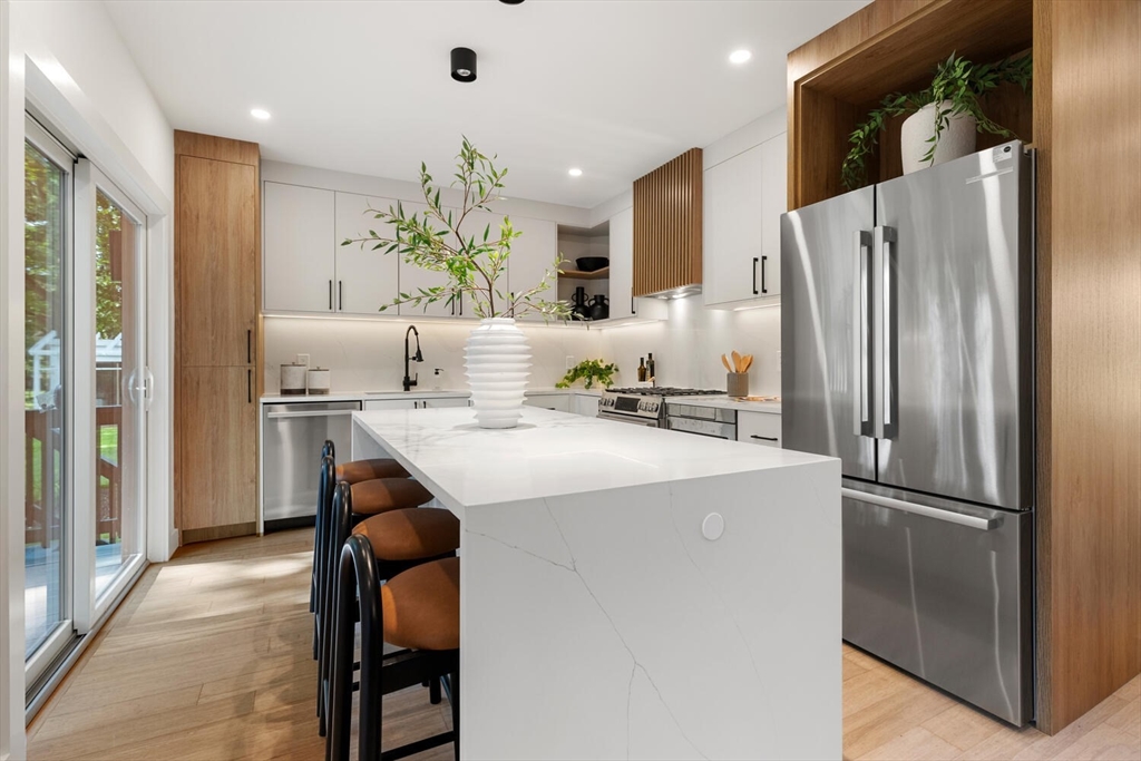 6 Wyman Court, Unit 6 Winchester, MA 01890 - Photo 6 of 35 a kitchen with kitchen island a counter top space cabinets and stainless steel appliances