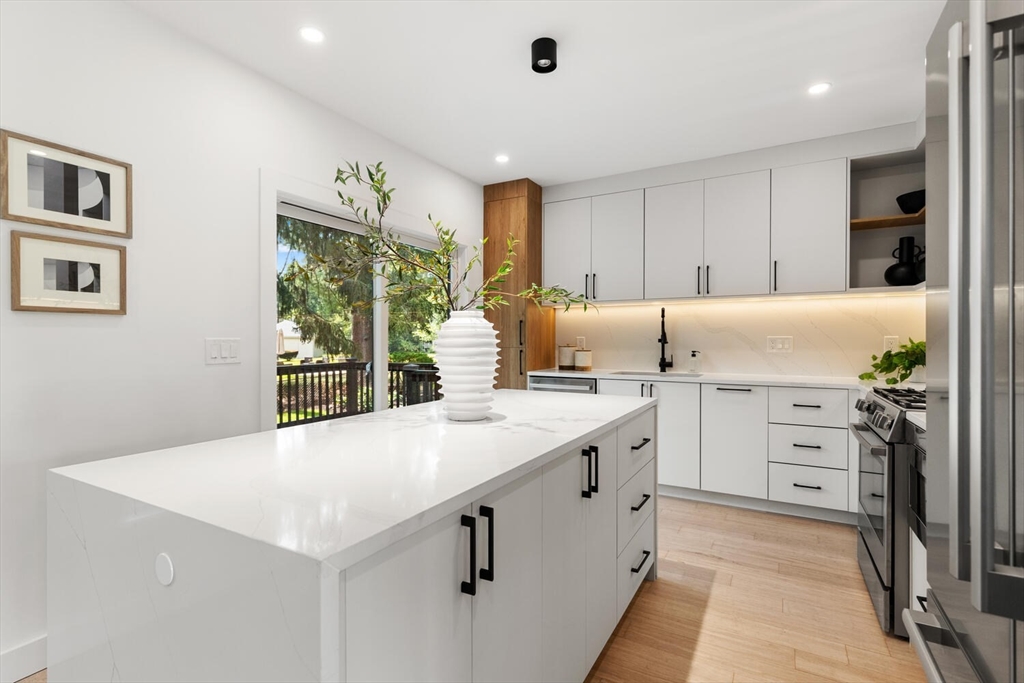 6 Wyman Court, Unit 6 Winchester, MA 01890 - Photo 7 of 35 a kitchen with white cabinets a sink dishwasher and a stove with wooden floor