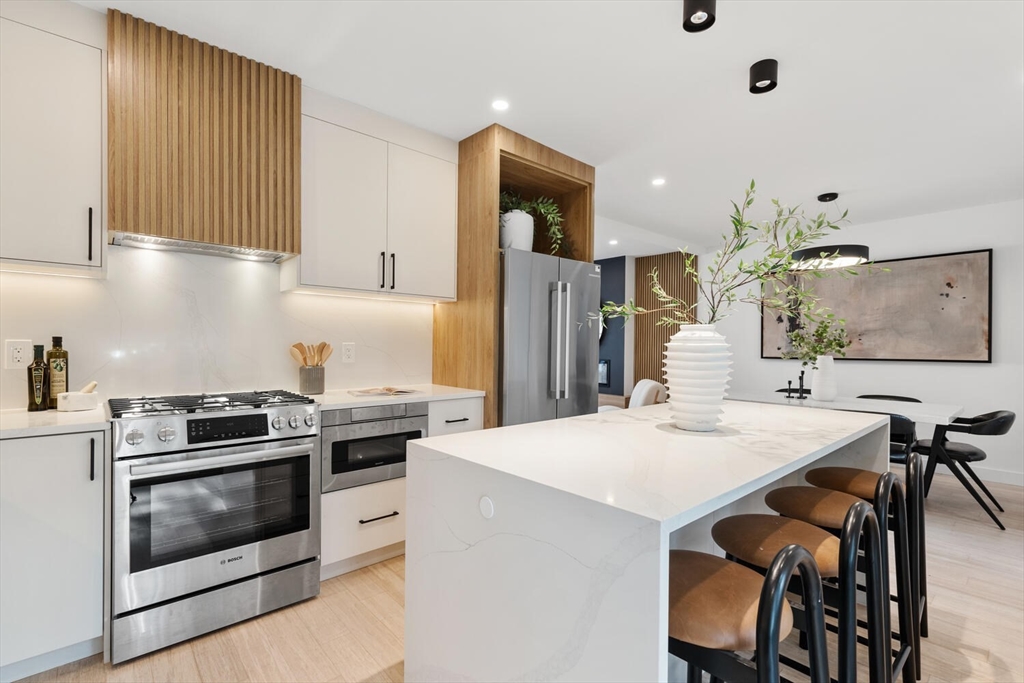 6 Wyman Court, Unit 6 Winchester, MA 01890 - Photo 8 of 35 a kitchen with a stove a refrigerator and a dining table