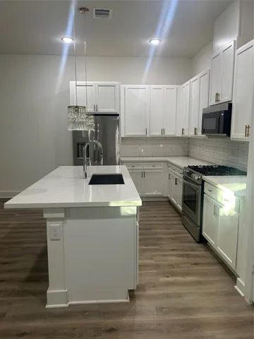 a kitchen with kitchen island a sink stainless steel appliances and cabinets