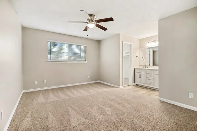 an empty room with windows and ceiling fan