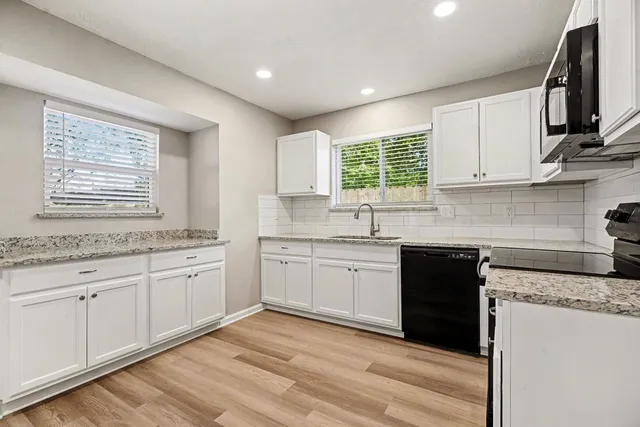 a kitchen with granite countertop cabinets stainless steel appliances a sink and a window