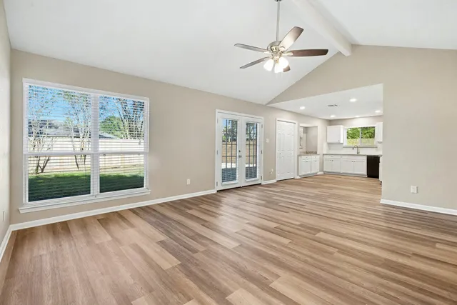 a view of an empty room with a window and wooden floor