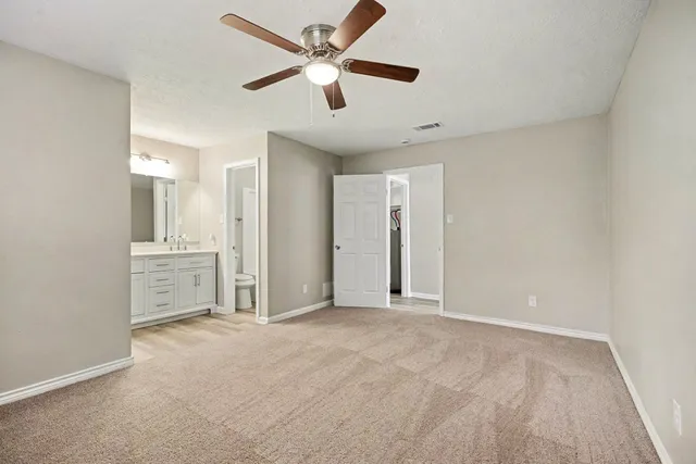 an empty room with chandelier fan and windows