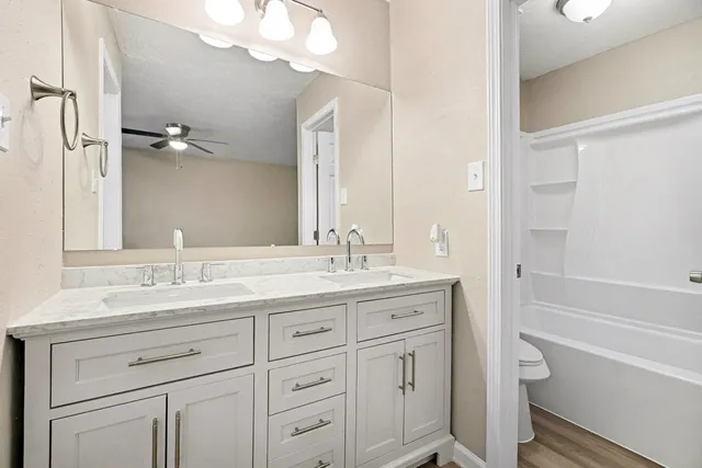 a bathroom with a granite countertop sink a toilet and a bathtub