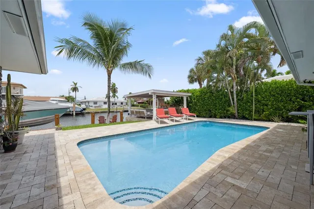 a view of a backyard with table and chairs potted plants and palm trees