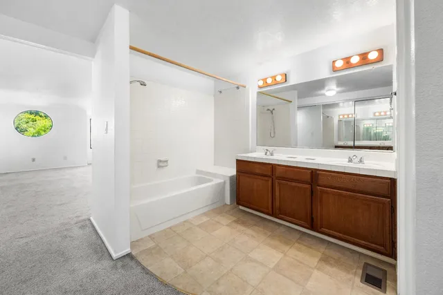 a spacious bathroom with a tub sink and mirror