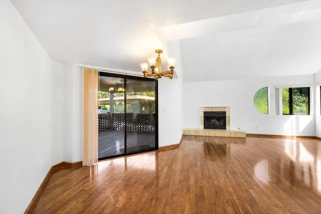 a view of an empty room with window and wooden floor