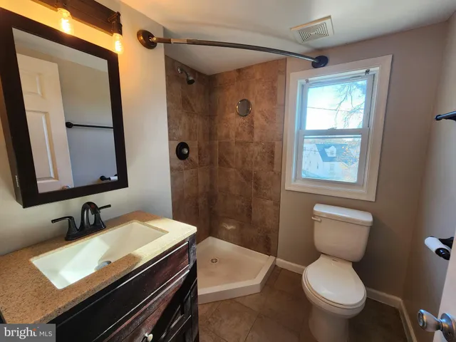 a bathroom with a granite countertop toilet sink and mirror