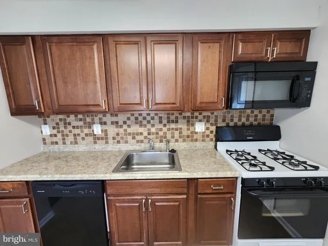 a kitchen with granite countertop a sink a stove and cabinets