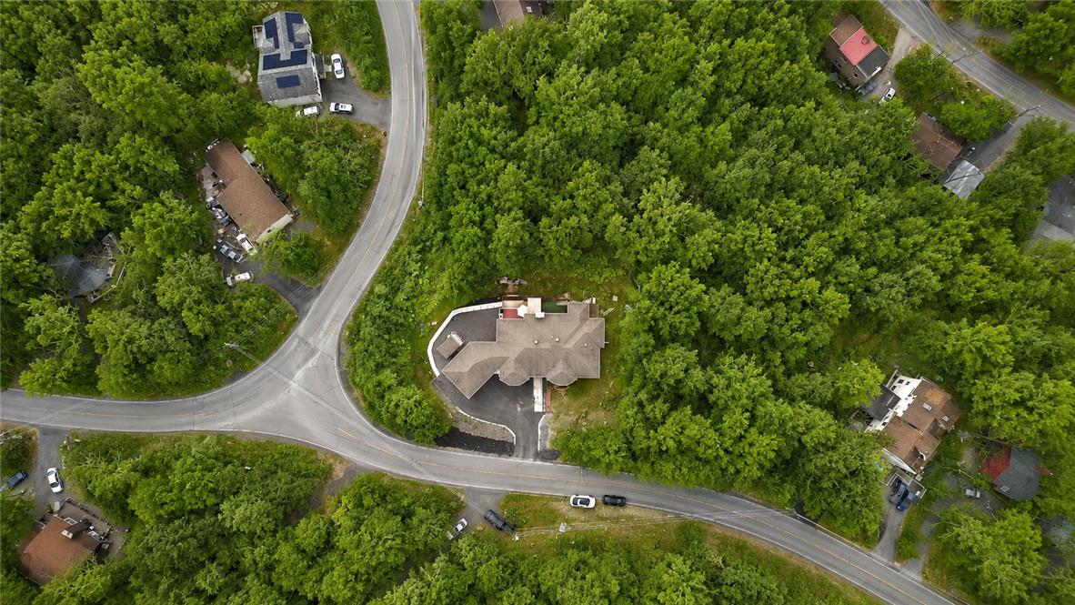 1007 Hampstead Road Bushkill, PA 18324 - Photo 53 of 72 An aerial perspective reveals a private residence nestled amidst a vibrant, green wooded landscape, featuring a paved driveway and ample seclusion.