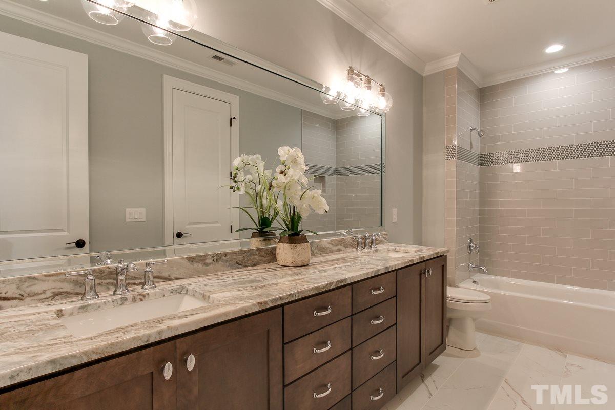 4913 Latimer Road Raleigh, NC 27609 - Photo 22 of 25 a bathroom with a granite countertop double vanity sink a large mirror a bathtub and shower