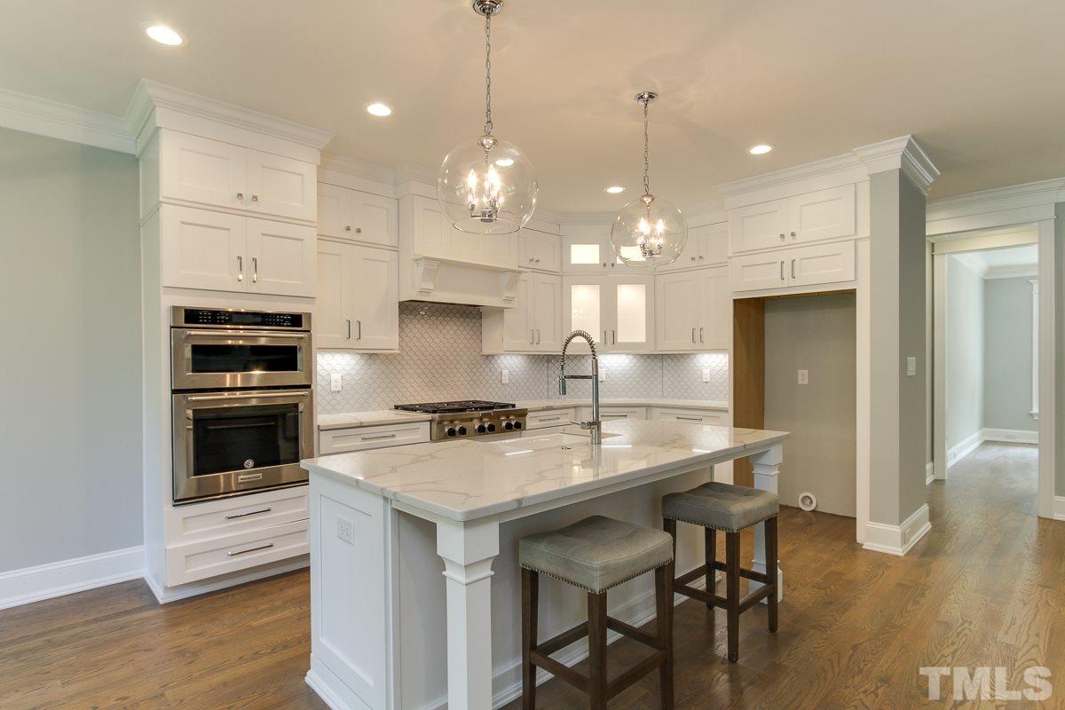 4913 Latimer Road Raleigh, NC 27609 - Photo 9 of 25 a kitchen with kitchen island a stove a table and chairs in it