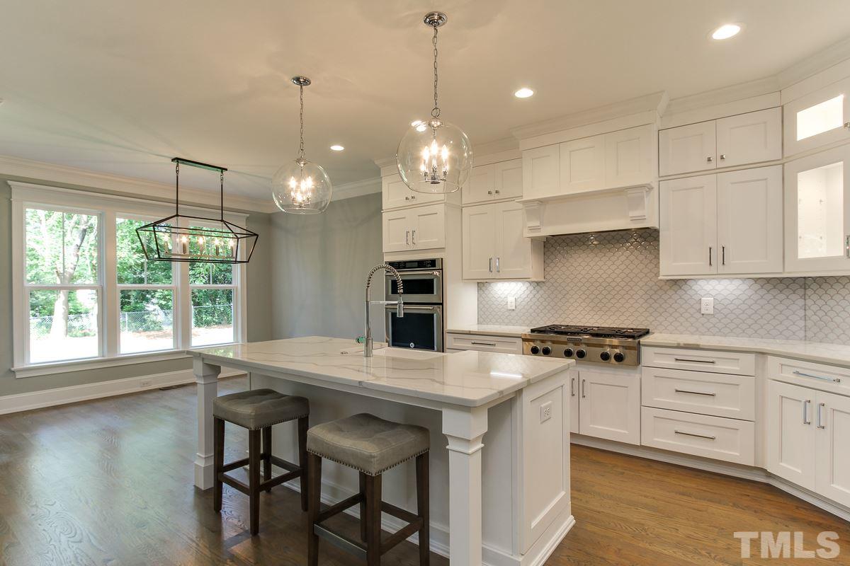 4913 Latimer Road Raleigh, NC 27609 - Photo 10 of 25 a kitchen with kitchen island a stove a table a sink and cabinets