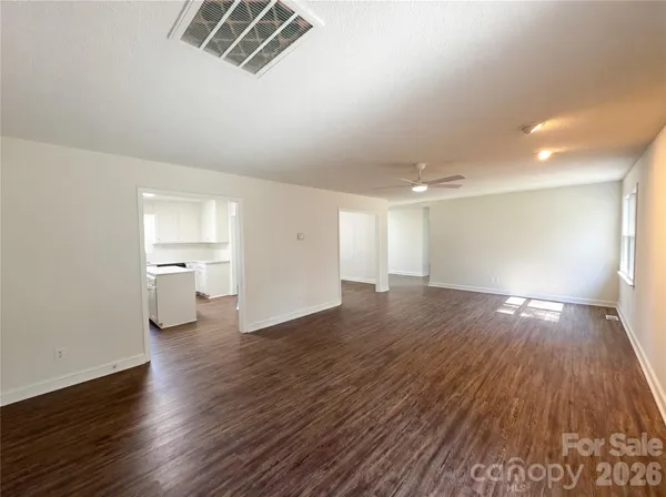 an empty room with wooden floor chandelier and windows