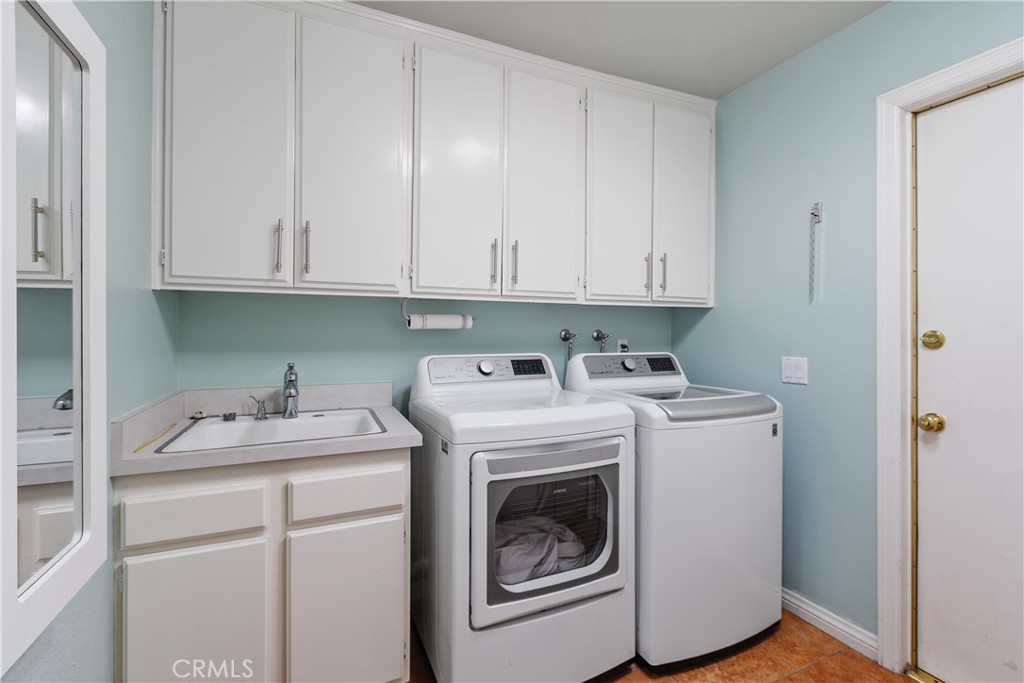 547 Vía Zapata Riverside, CA 92507 - Photo 28 of 36 The laundry room has been updated with spacious cabinets and a sink. The attached garage is to the right.