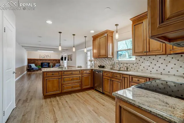 a kitchen with stainless steel appliances granite countertop a sink a stove and a wooden cabinets