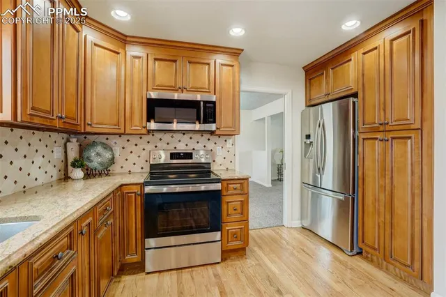 a kitchen with granite countertop wooden cabinets stainless steel appliances and a wooden floor