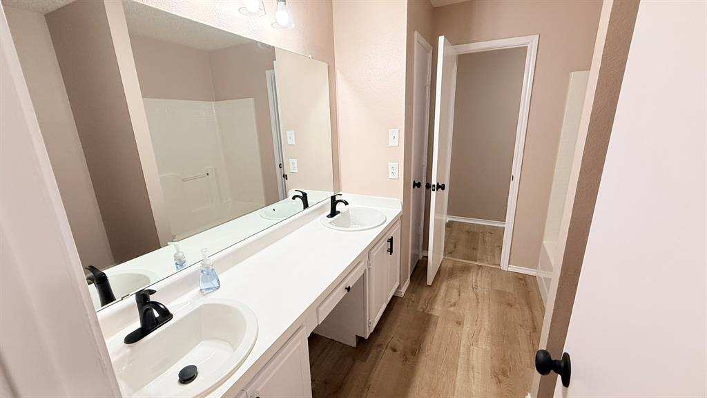 12259 Rim Rock Road Dallas, TX 75253 - Photo 12 of 17 Full bathroom with double vanity and light wood finished floors