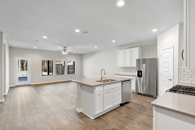 a large kitchen with stainless steel appliances a large counter top a stove and a refrigerator