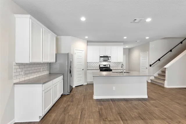 a view of an empty room with wooden floor and stairs