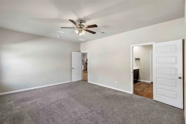 a view of an empty room with chandelier fan and a window