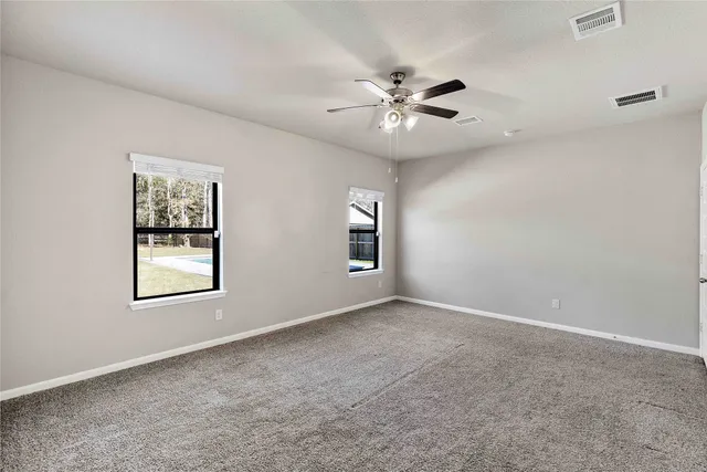 an empty room with windows and fan