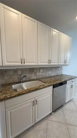 a kitchen with granite countertop white cabinets and sink