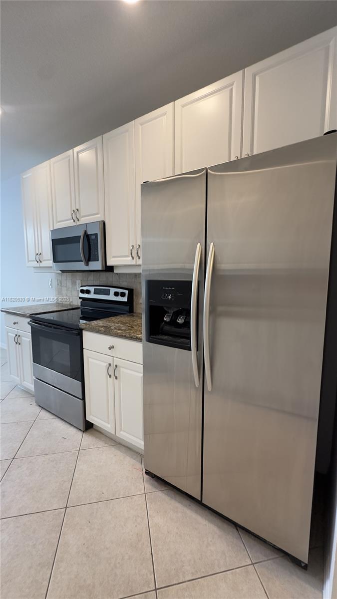 1587 Frederick Small Road Jupiter, FL 33458 - Photo 7 of 30 a kitchen with kitchen island granite countertop cabinets and white appliances