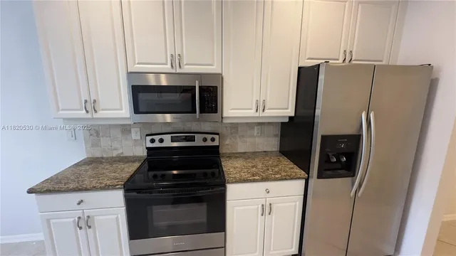 a kitchen with granite countertop white cabinets and stainless steel appliances