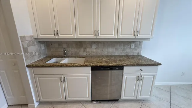 a utility room with granite countertop cabinets and sink
