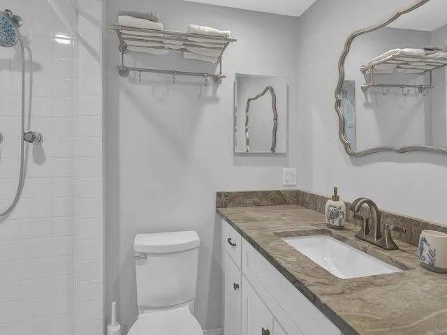a bathroom with a granite countertop sink a toilet and a mirror