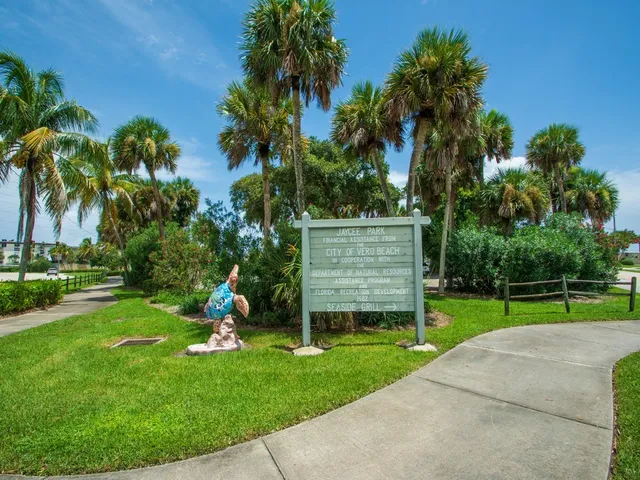 front view of a house with a yard and palm trees